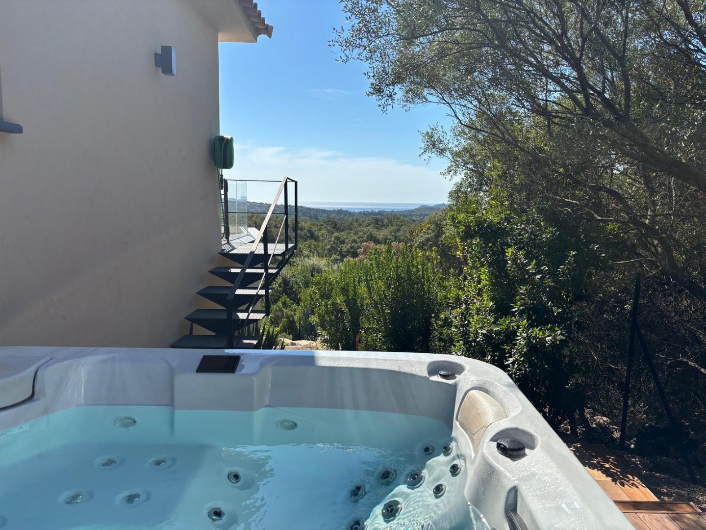 Le spa extérieur installé sur sa terrasse en bois, la mer visible au-dessus du maquis.