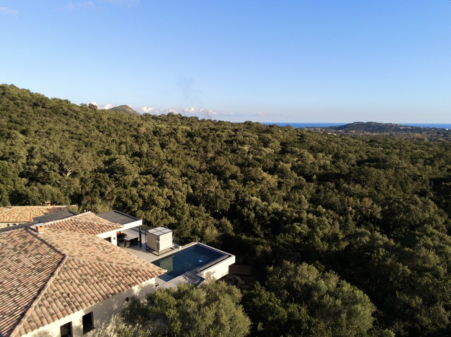 La villa dans son environnement de maquis, vue depuis le ciel, la mer à l’horizon.