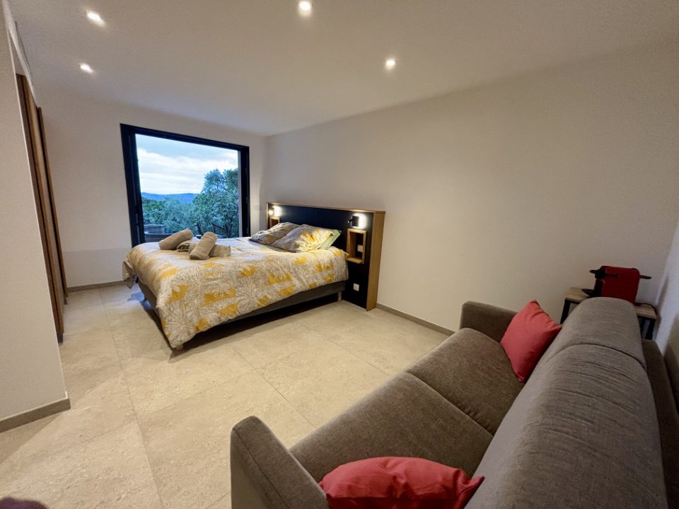 Chambre 4, suite parentale : lit double et banquette, fenêtre ouverte sur le maquis.