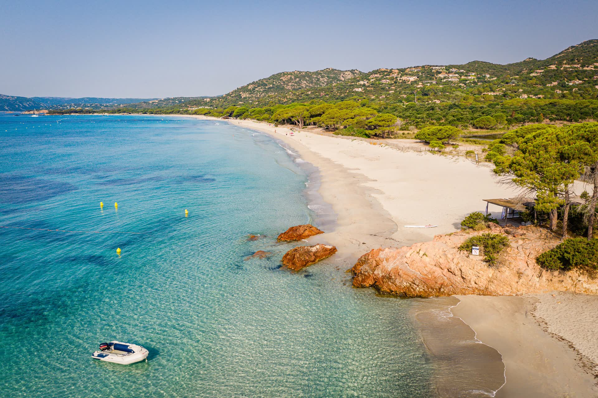 La plage de Palombaggia vue du ciel : la mer turquoise, le sable clair, les pins parasols et les collines du maquis.